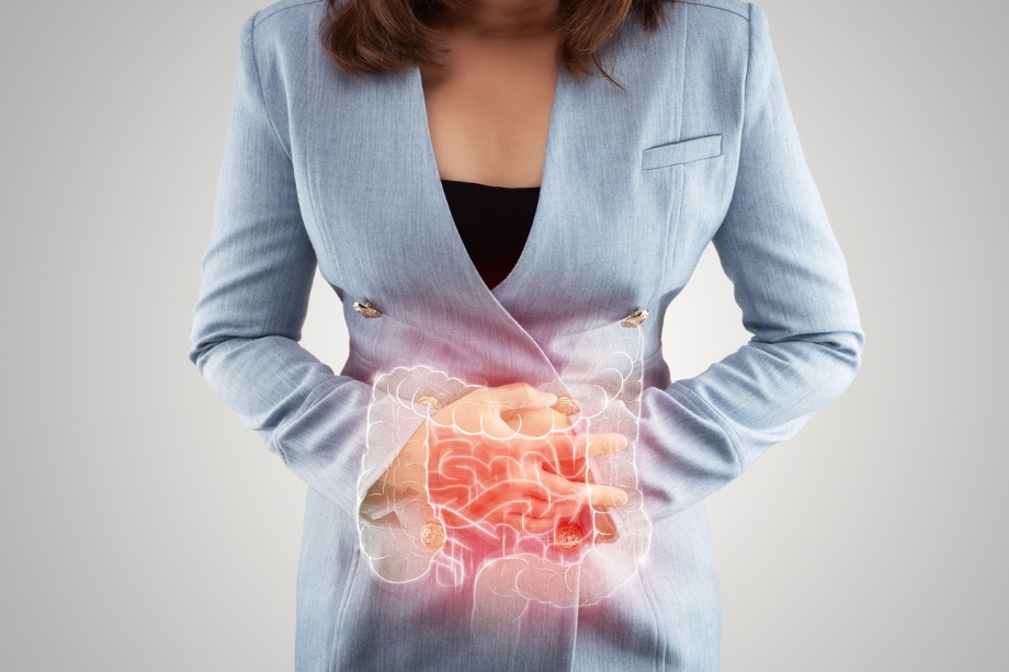 A woman holding her abdomen, with an illustration of the digestive system highlighted in red