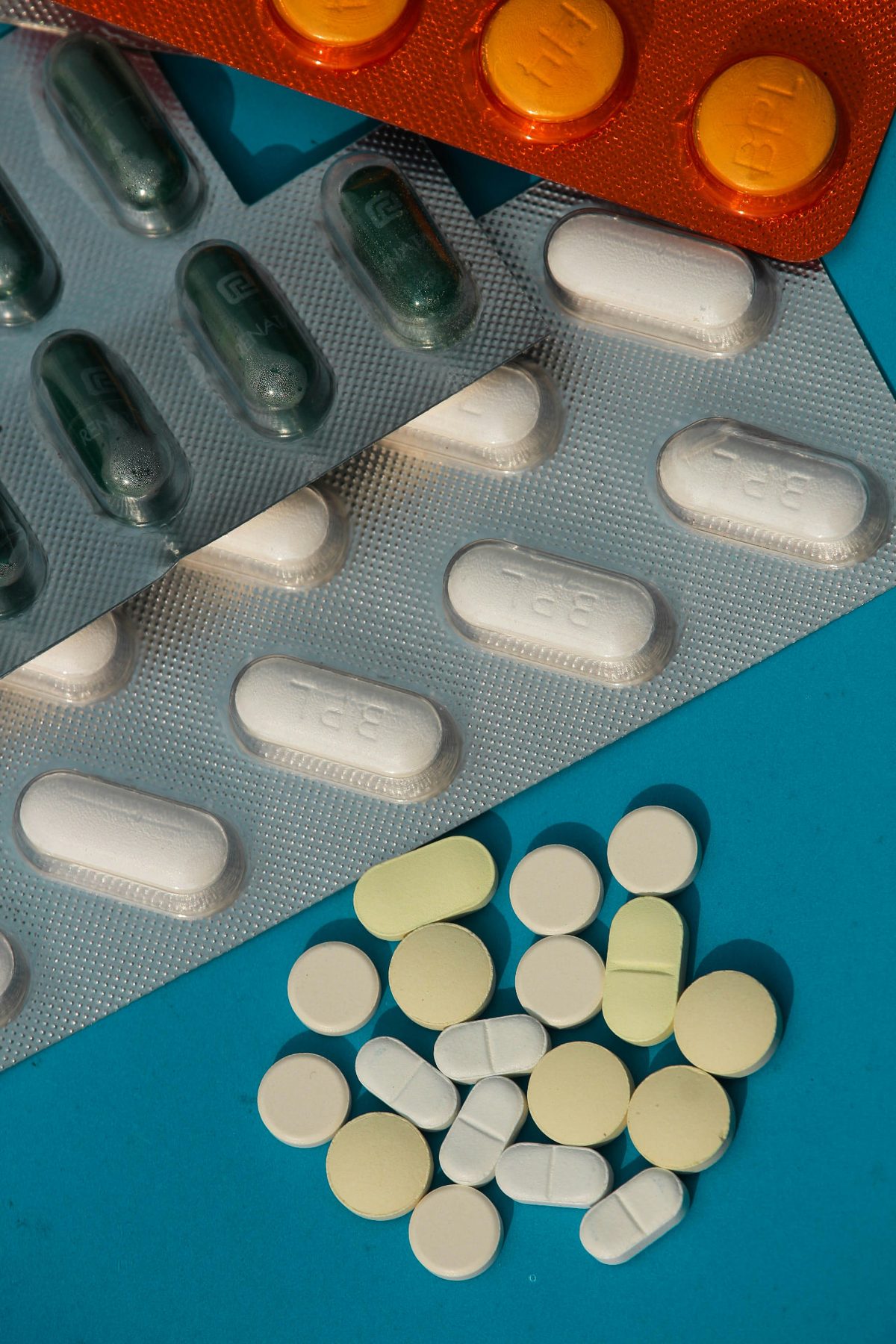 Blister packs of tablets and capsules with loose tablets on a blue background