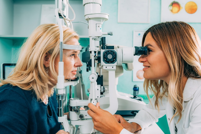 A female ophthalmologist examining a woman’s eyes with a slit-lamp microscope in a clinic